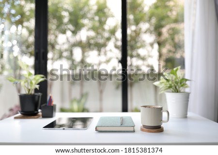 Work station with coffee mug and notebook and tablet decorating with green plant home office