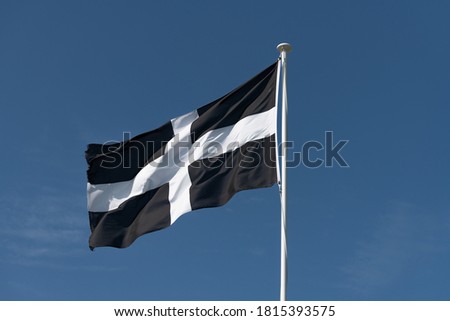 national flag of Cornwall fluttering in the breeze against a blue sky background