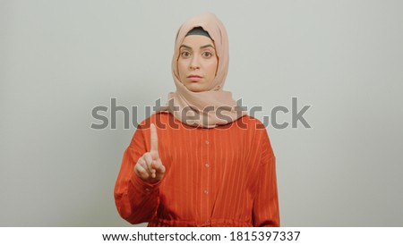 Come on, this is a mistake! Young woman wearing hijab, warning with finger gesture, saying no, be careful, do not approve sign. Studio shot isolated on white background.