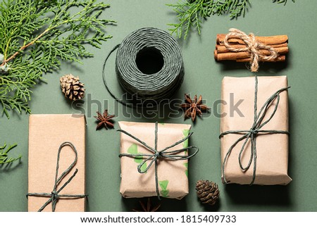 Eco friendly Christmas composition with gift boxes in craft reusable paper and natural decor on green background top view. Zero waste environmentally friendly Christmas concept.
