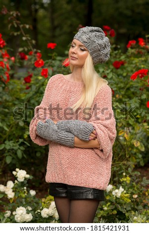 Woman posing in autumn garden in pink sweater and hat
