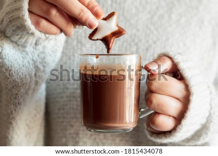 Girl hands dipping cookie in hot chocolate