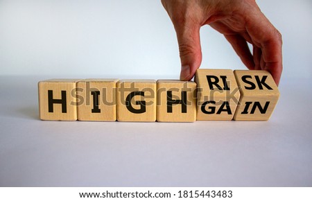 Cube form the expression 'high risk, high gain'. Male hand. Beautiful white background. Business concept, copy space.