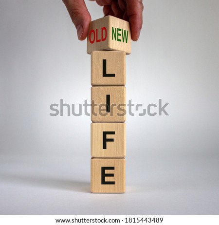 Hand is turning a cube and changes the words 'old life' to 'new life'. Beautiful white background. Business concept, copy space.