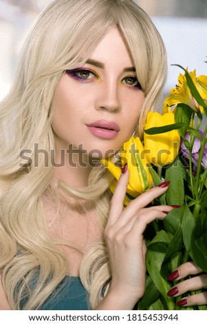 Fashion model with creative professional make-up with purple and yellow color  and flower in hand. SPA and wellness, bodycare and skincare concept.