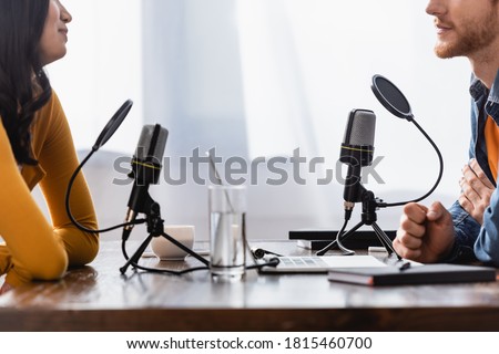 partial view of young woman and interviewer near microphones in radio studio