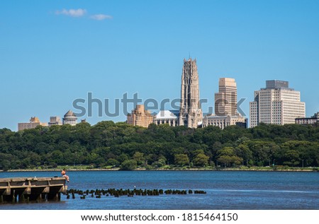 View of New York on the Hudson River walking path. With a men sitting on a dock and a view of Grant's tomb and Riverside Church.  Note model release attached. Royalty-Free Stock Photo #1815464150