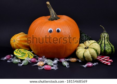 Spooky halloween pumpkin with eyes and candies stock images. Different types of pumpkins and squash autumn still life stock images. Decorative halloween pumpkins on a black background stock photo