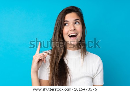 Teenager girl over isolated blue background intending to realizes the solution while lifting a finger up
