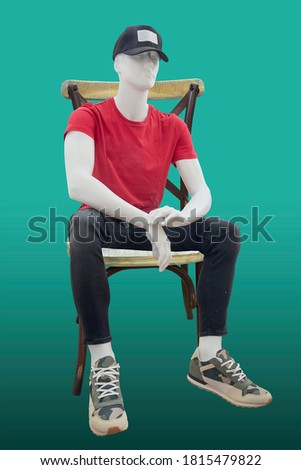 Sitting male mannequin isolated on green background. No brand names or copyright objects.