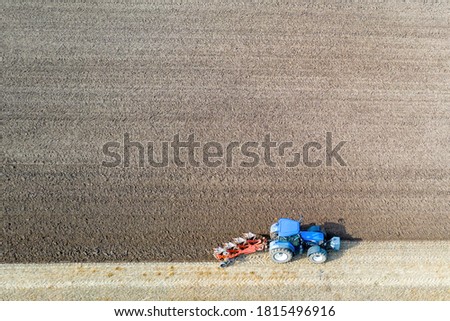 An aerial view of a tractor plowing a barren field for future crops. 