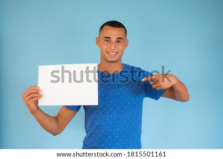 Handsome young man is holding a sheet of paper and pointing on it