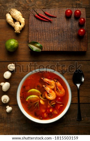 Tom yam soup with shrimp and lime in a light plate on the table ginger, lime and mushrooms.