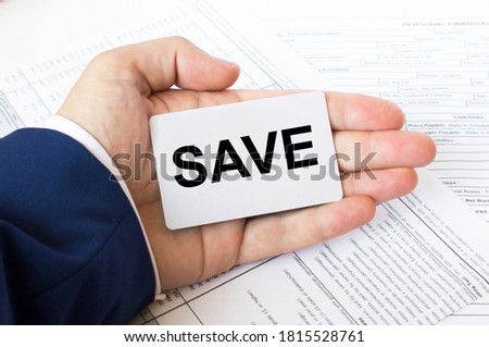 A mans hand is on the financial tables holding a business card with the inscription Save. Business concept photo