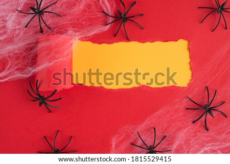 Halloween concept. Top above overhead view photo of torn red paper over yellow background with copyspace spiders and net over it