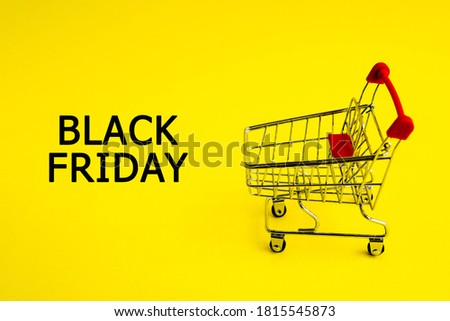 The shopping cart and the words black Friday on a yellow background. Theme of purchases and sales.