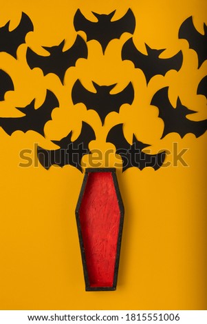 open coffin with red upholstery from witch fly black handmade paper bats. halloween concept on orange background
