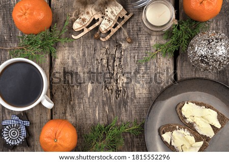 A cozy Christmas composition of Coniferous branches, tangerines, a Cup of coffee and sandwiches, a Notepad and a retro camera on a natural wood background. The concept of New year and Christmas.