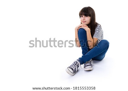 young 10 year old girl sit on floor rest with hands on knee and smile into camera with copy space isolated on white Royalty-Free Stock Photo #1815553358