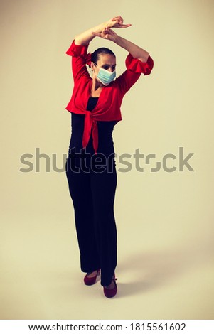 woman in black pants and red bullfighter dancing flamenco sevillanas with mask