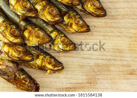 Golden, smoked sprats arranged on wooden cutting board