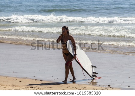 A closeup shot of a beautiful young lady with a surfing board on the beach