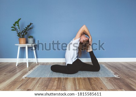 Woman practicing yoga at home, blue wall background, copy space