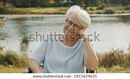 Pensive old woman in the wheelchair sitting near the river . High quality photo