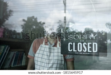 The woman store owner hanging closed sign in front door of her shop. Effect of corona virus or covid-19 outbreak 2020. 