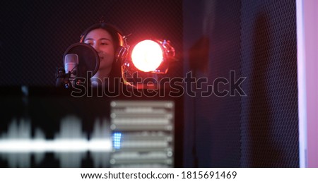 Young asian woman attractive musicians happy singing recording new song in modern sound studio. Beautiful female working and singing near microphone in studio on dark background.