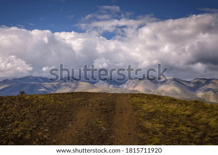 Stunning mountain landscape. Thunderstorm front over the mountain range, sun's rays shine through fluffy clouds. Beautiful sky. Road trips, off-road in Altai, Siberia.