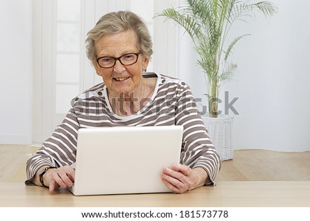 Smiling senior woman at home connected on internet 