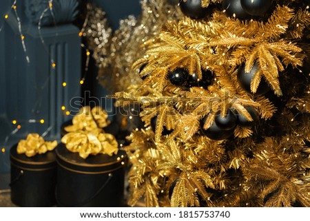 Photo of luxury gift boxes under Christmas tree, New Year home decorations, golden wrapping of Santa presents, festive tree decorated with garland, baubles, traditional celebration. Copy space
