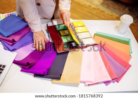 Young stylist helping customer to choose clothes colors