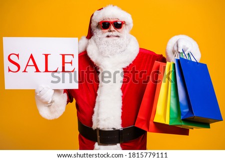 Portrait of his he nice attractive cheerful confident fat Santa holding in hands things buyings board sale advert ad black Friday isolated bright vivid shine vibrant yellow color background