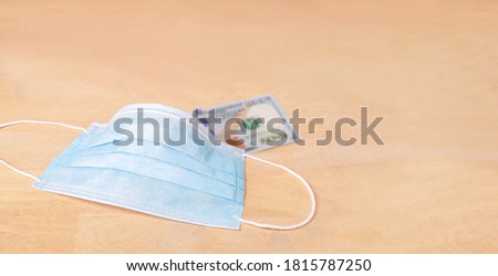 Medical mask, Medical protective mask cover blur one hundred dollar banknote on wood table background, Protect your self from epidemic and protect your investment concept