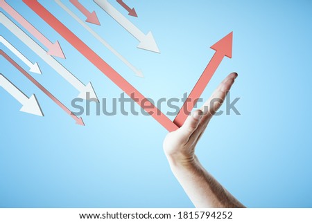 Hand holds a red arrow on blue background. Business and challenge concept.