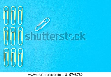 yellow paper clips are lined up the same. white paper clip on the side stands out