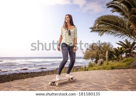 beautiful young skater woman with a longboard near the sea