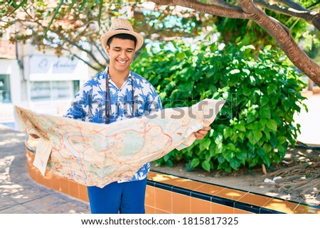 Young arab tourist man using vintage camera and city map at the park.