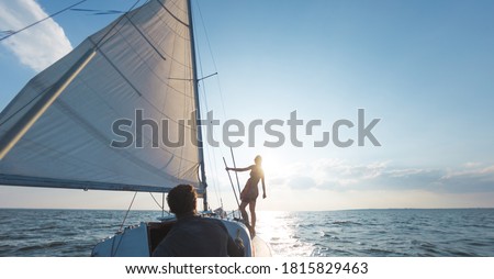 Romantic couple in love on sail boat at sunset under sunlight on yacht, A man and a woman are traveling on a sailing yacht. Royalty-Free Stock Photo #1815829463