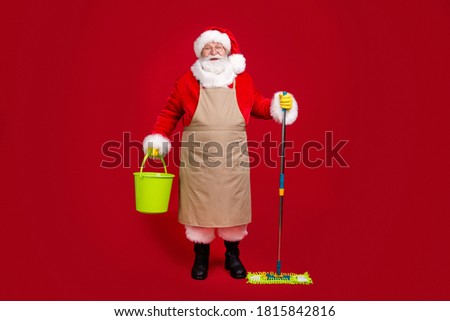 Full length photo of santa claus grey beard hold mop bucket wear x-mas costume apron coat headwear glasses latex gloves boots glasses isolated red color background