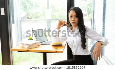 Portrait of female concentrating on her work with books, laptop and supplies on worktable in the office.
