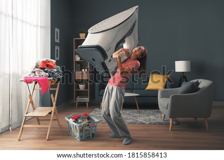 Woman doing household chores and holding a huge heavy iron, stress and housework concept Royalty-Free Stock Photo #1815858413