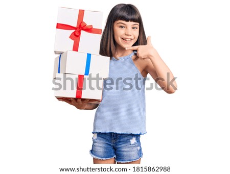 Young little girl with bang holding gifts smiling happy pointing with hand and finger 