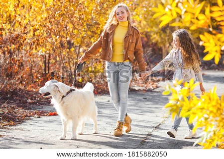 Two cute girls walking with their pet. Sisters and dog at autumn background