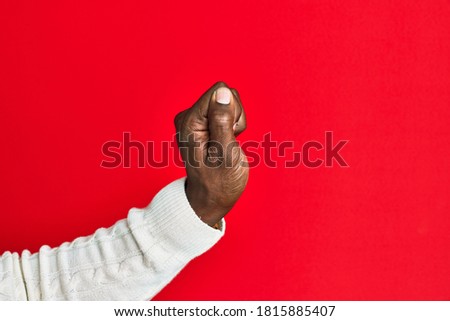 Arm and hand of african american black young man over red isolated background holding blank space with thumb finger, business and advertising 