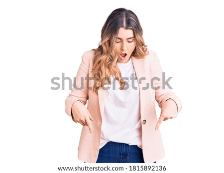 Young caucasian woman wearing business clothes pointing down with fingers showing advertisement, surprised face and open mouth 