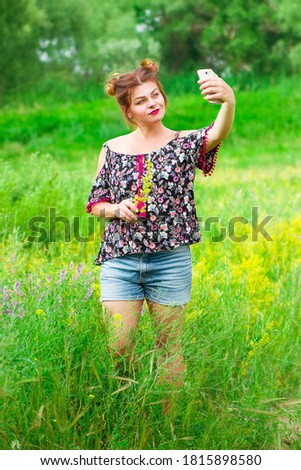 happy girl in the field makes a selfie on the phone