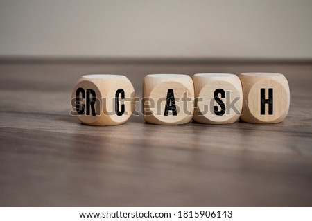 Cubes and dice with the words crash and cash on wooden background